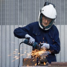 Carpentiere metallico indossa un casco integrale bianco con visiera protettiva mentre effettua una lavorazione metallica