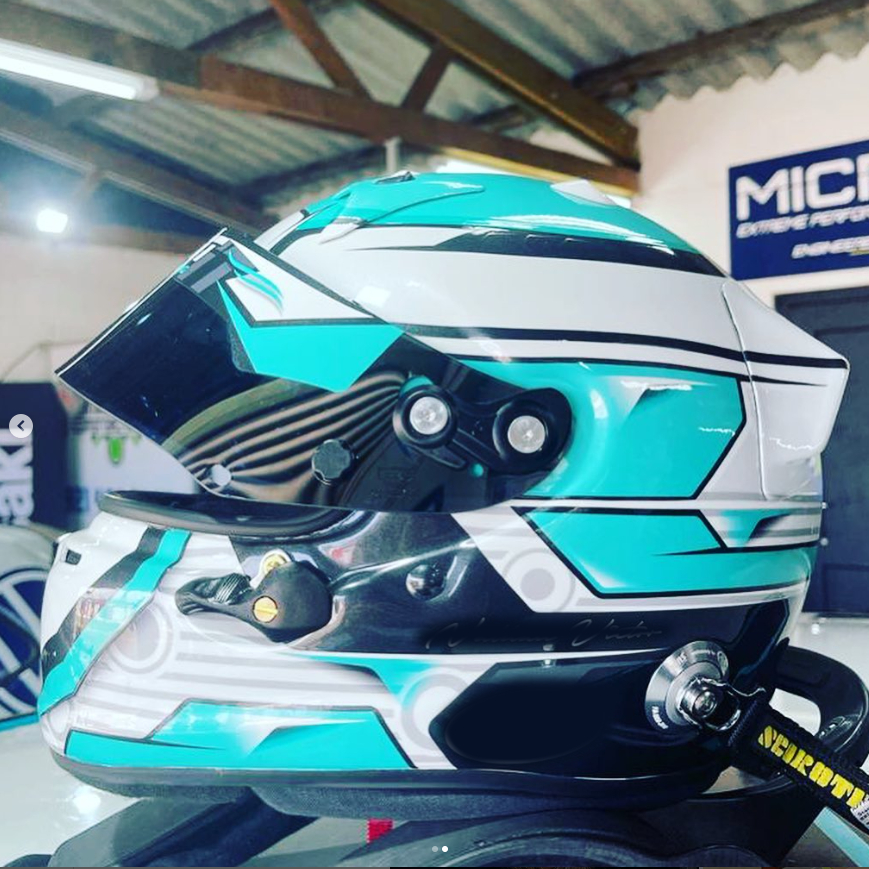 casco da moto bianco con dettagli geometrici azzurri. Ha una visiera nera di piccole dimensioni.